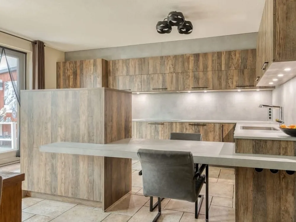 U-keuken in houtlook met betonlook werkblad, uitgebouwde eettafel en AEG-apparatuur