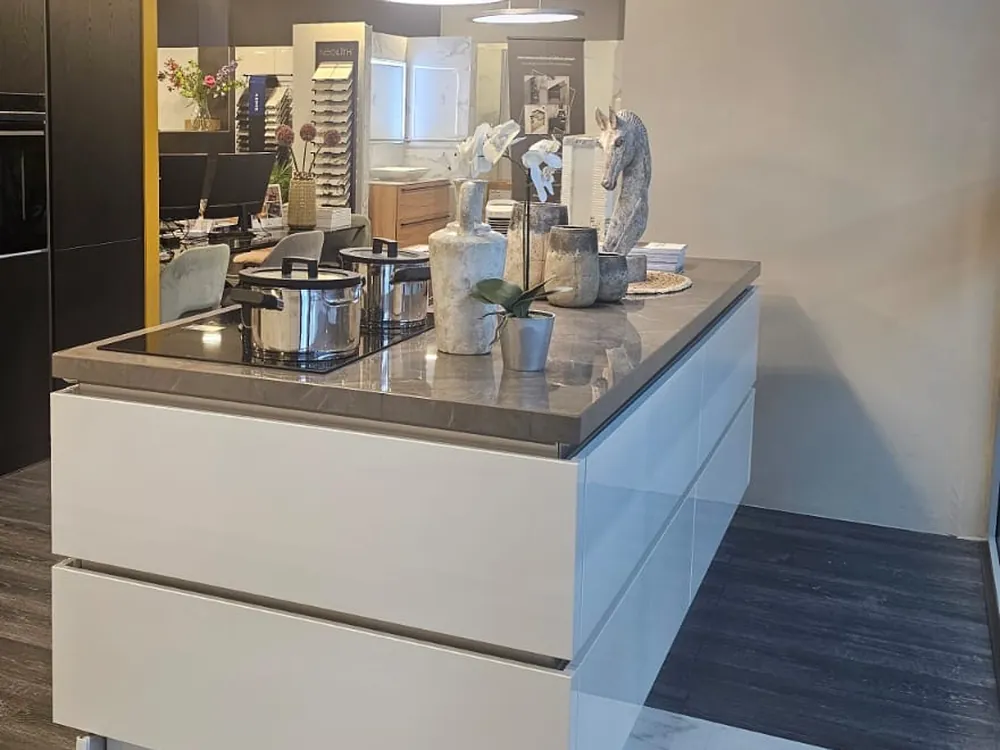 Witte greeploze Nobilia eilandkeuken met grijs marmerlook werkblad, Bora inductie en zwarte kastenwand met Siemens ovens